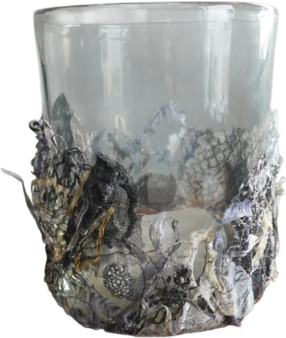 Gegnsætt glas með hvítu, gráu og svörtu blúndulíku skrauti á neðri hlutanum.